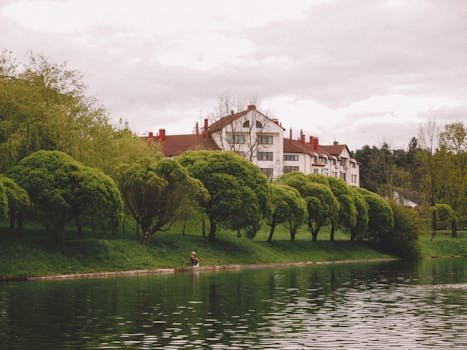 pexels-photo-31993942-31993942 Serene riverside scene with lush trees and charming houses, perfect for peaceful nature settings.